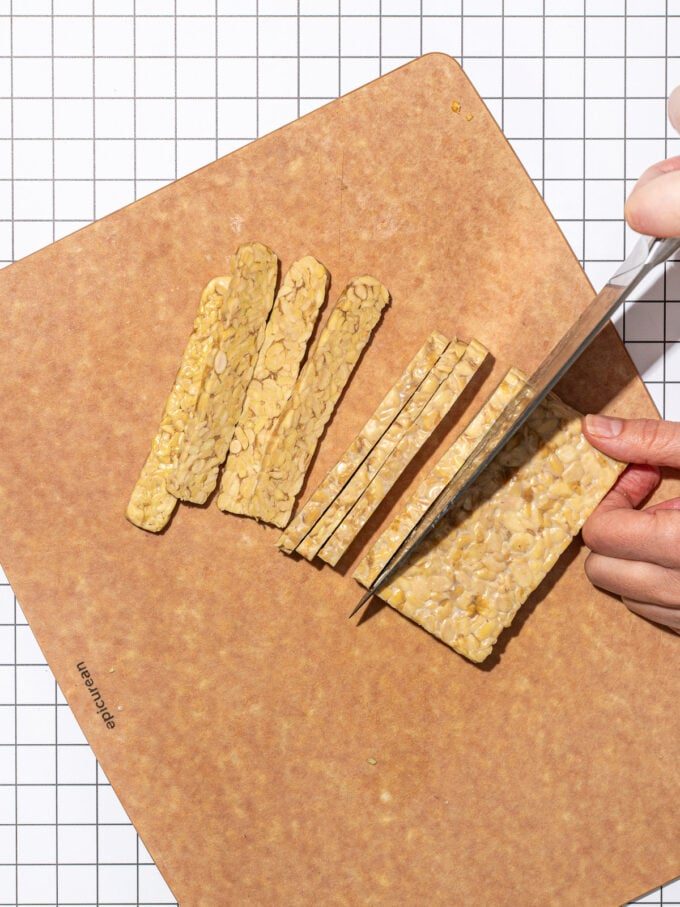hand slicing tempeh into strips with knife