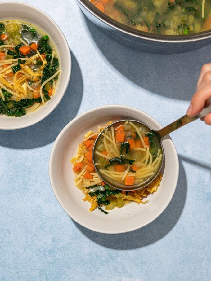 ladling tofu chicken noodle soup into a white bowl