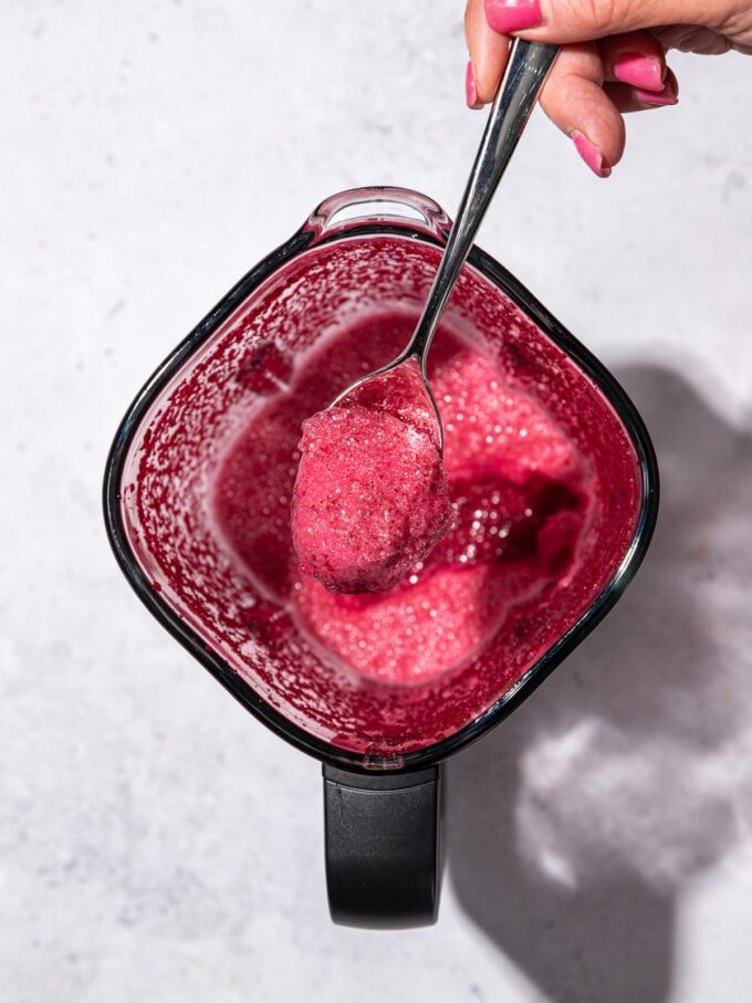 hand scooping foam off of beet juice in blender