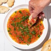 hand dipping bread into tomato, parsley and olive oil bread dip