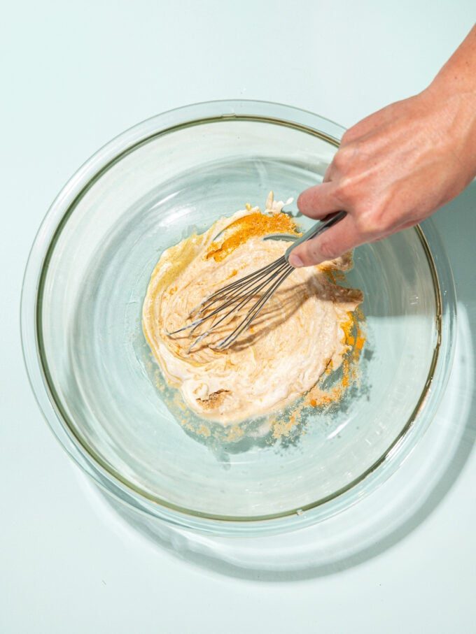 hand whisking mayo dressing in glass bowl