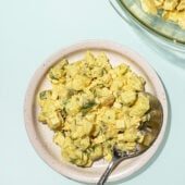 white plate topped with vegan potato salad, with a spoon.