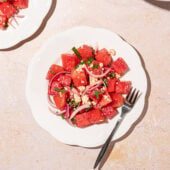 white plates topped with watermelon mint salad with a fork resting beside it